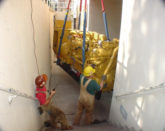 Caterpillar 3512 diesel engine generator being rigged into a basement doorway.