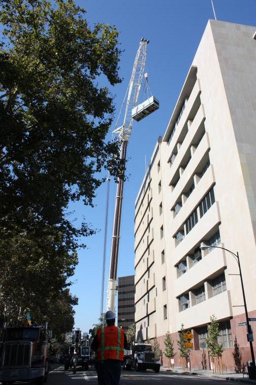 26 ton Allison gas turbine generator being craned from the top of a 9 story commercial building.